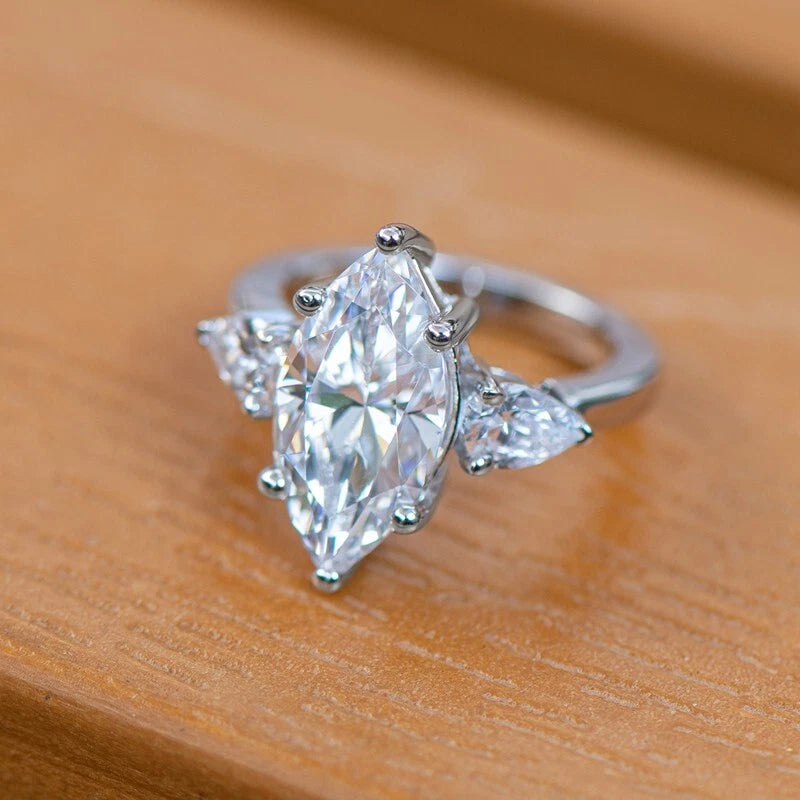 Silver ring with a large pear-shaped diamond on a wooden surface