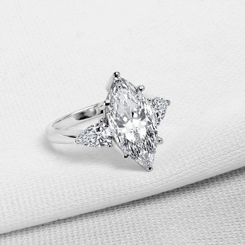 Diamond ring with a pear-shaped center stone on a light gray background
