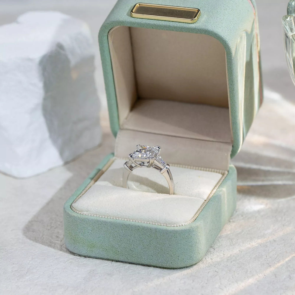 Diamond ring in a light blue jewelry box on a white surface
