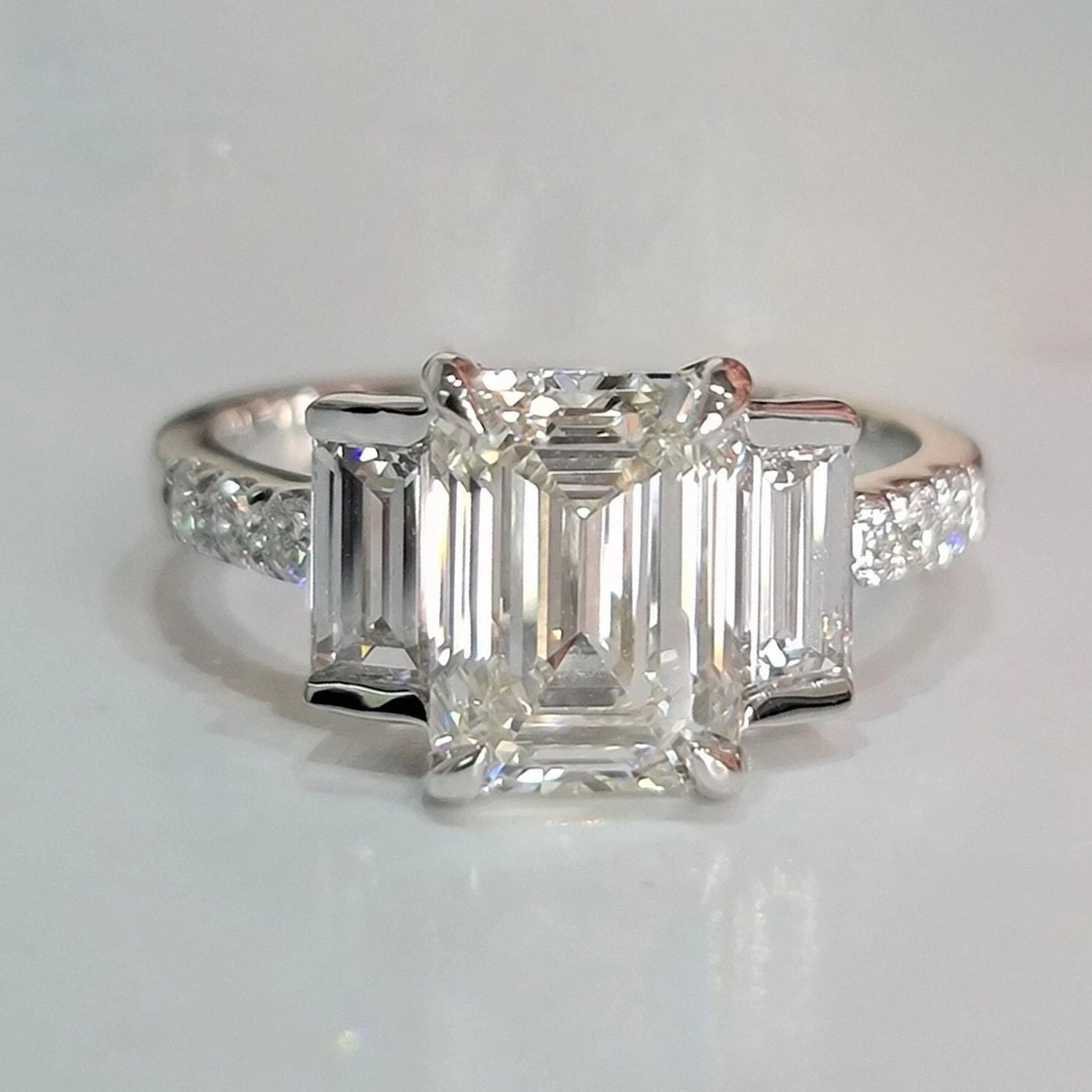 Diamond ring with emerald-cut stones on a light gray background