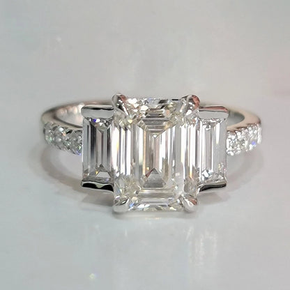 Diamond ring with emerald-cut stones on a light gray background