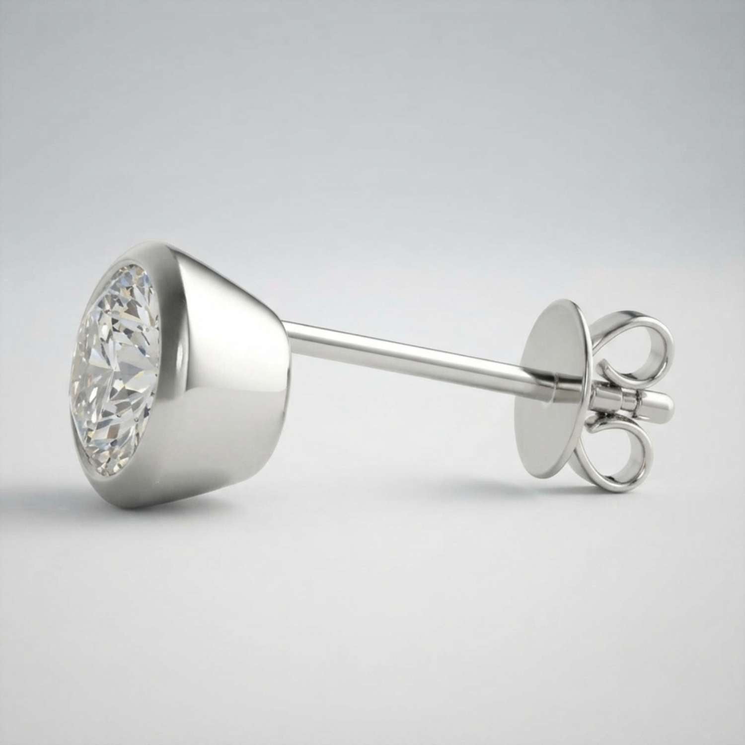 Sleek and secure push-back bezel diamond studs resting on a clean surface.
