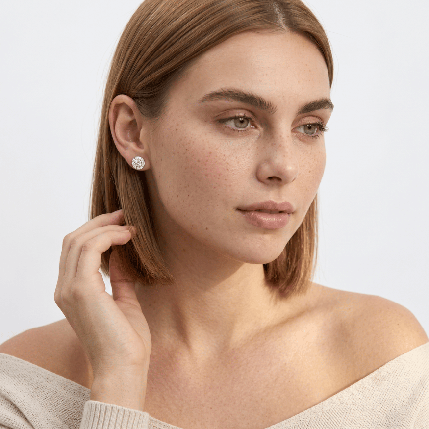 Close-up of a woman touching her hair while wearing a small round silver stud earring with a clear gemstone.