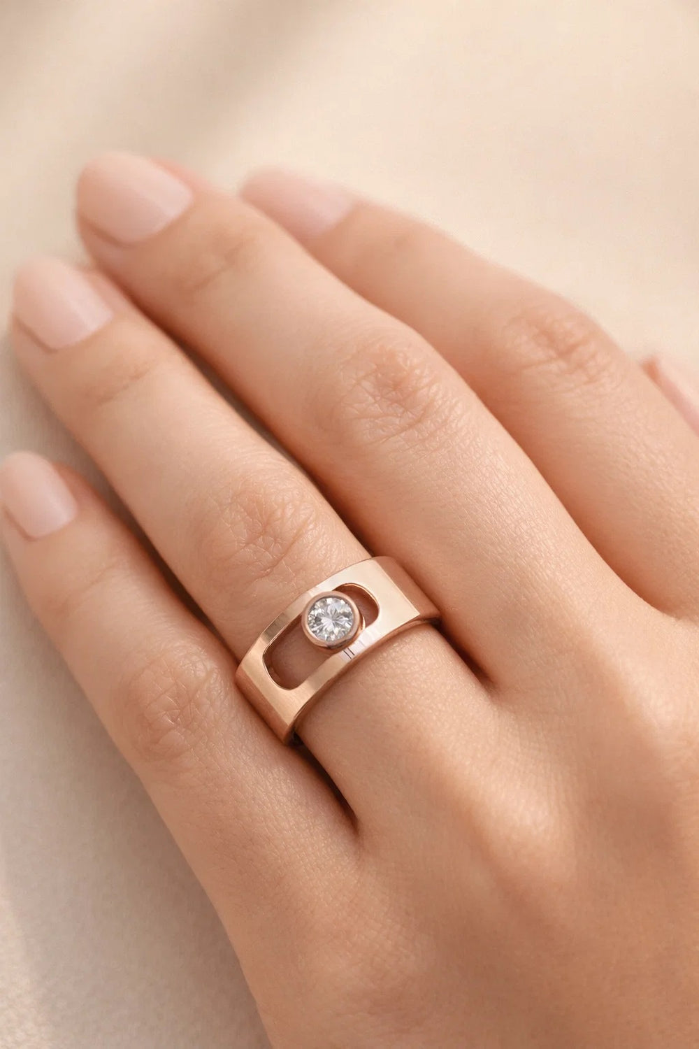 Rose gold ring with a diamond on a hand against a beige background