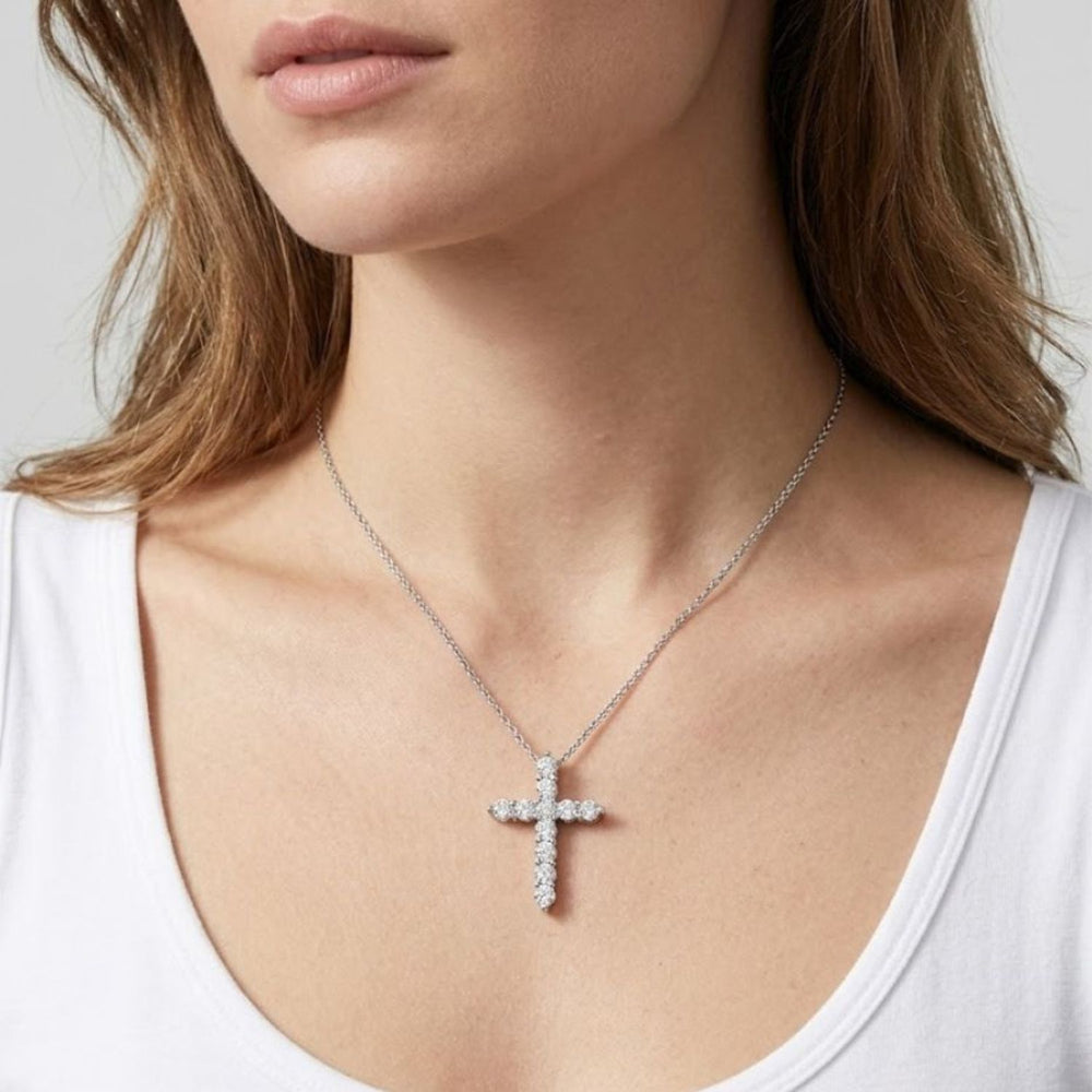 Close-up view of a woman wearing a white gold cross pendant necklace adorned with round diamonds.