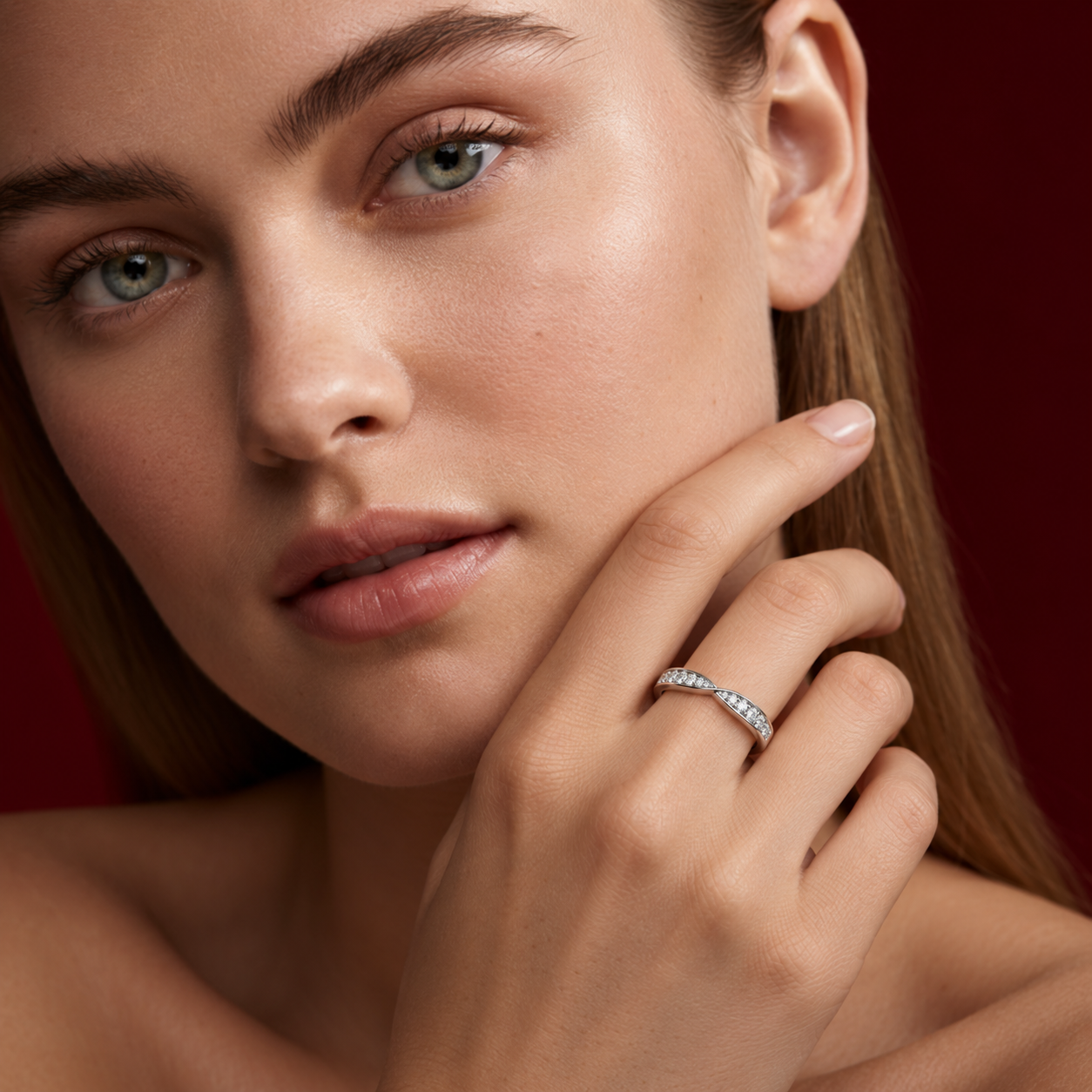Close-up portrait of a woman holding her hand to her cheek, wearing a slender white gold ring with small clear diamonds.