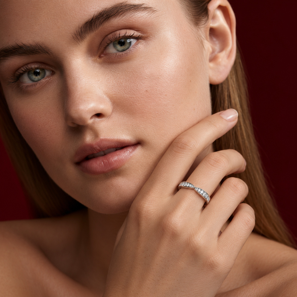 Close-up portrait of a woman holding her hand to her cheek, wearing a slender white gold ring with small clear diamonds.