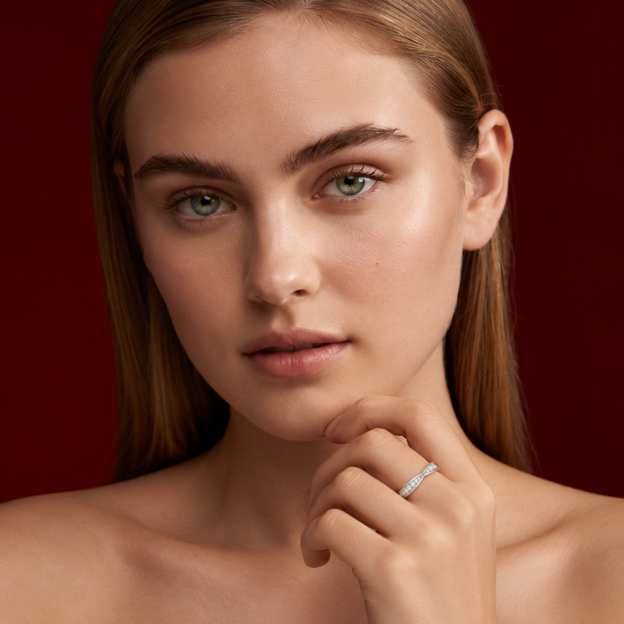 Frontal portrait of a woman resting her hand near her chin, wearing a white gold twisted band ring set with small diamonds.