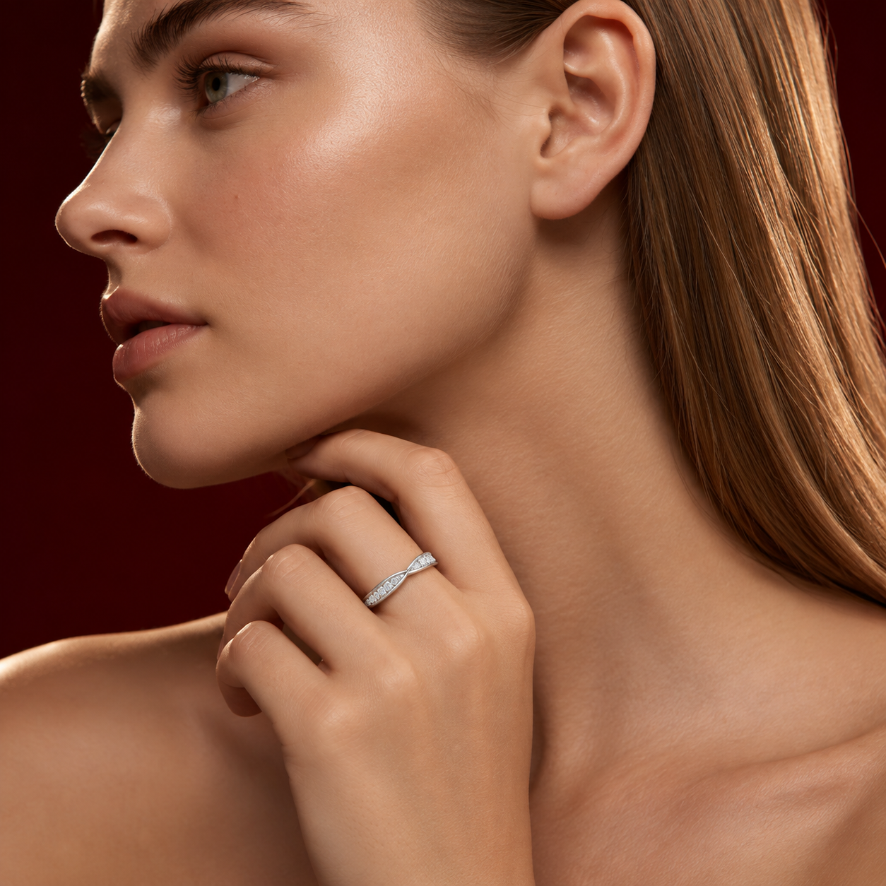 Side profile shot of a woman with her hand resting under her chin, wearing a delicate white gold twisted diamond band ring.
