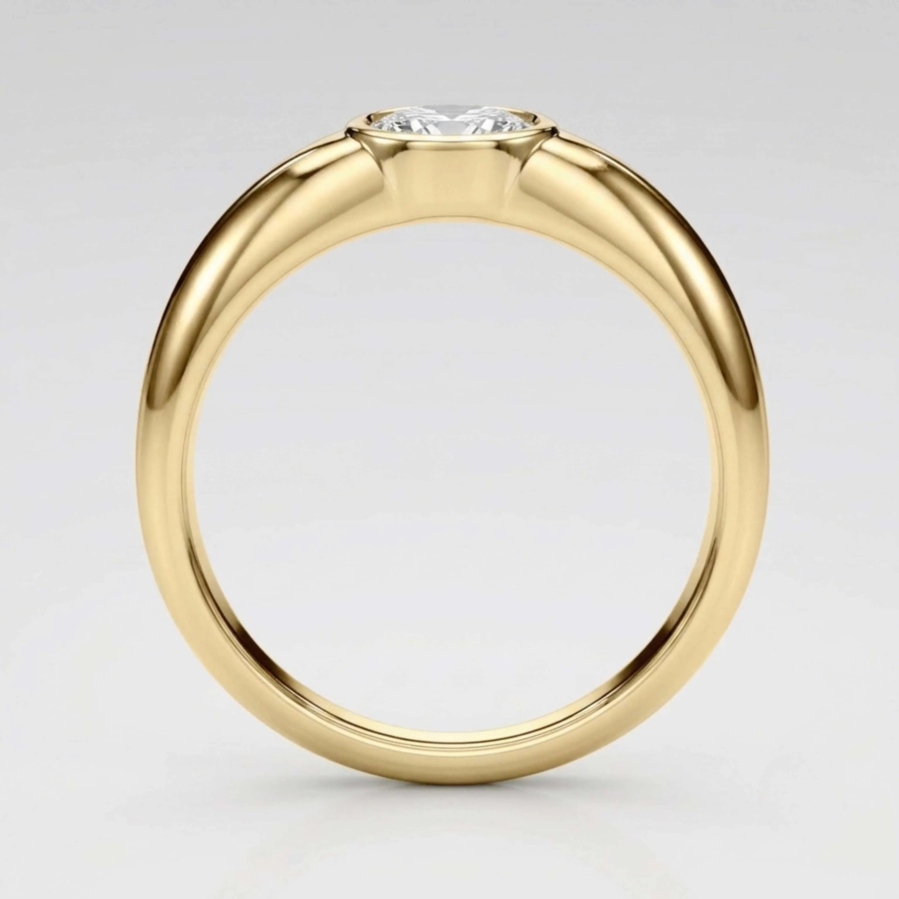 A yellow gold solitaire ring with a round brilliant-cut diamond set in a four-prong setting, shown on a light gray gradient background.